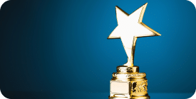 A golden trophy with a star-shaped top sits against a blue background. The trophy's base is intricately detailed, providing an elegant and distinguished appearance. The light shines brightly on the star, making it the focal point of the image.